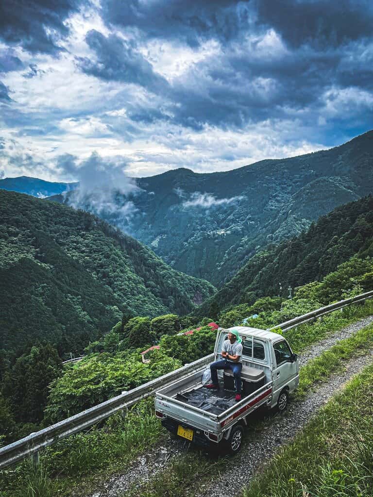 奥多摩の山々を望む軽トラックと人